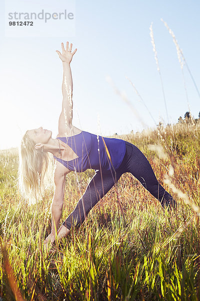 Reife Frau beim Yoga auf dem Feld