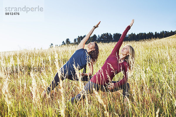 Reife Frauen  die Yoga auf dem Feld praktizieren