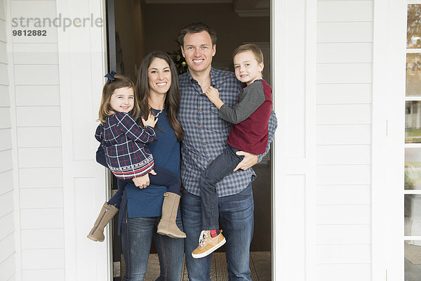 Porträt von Eltern und zwei Kindern vor der Haustür