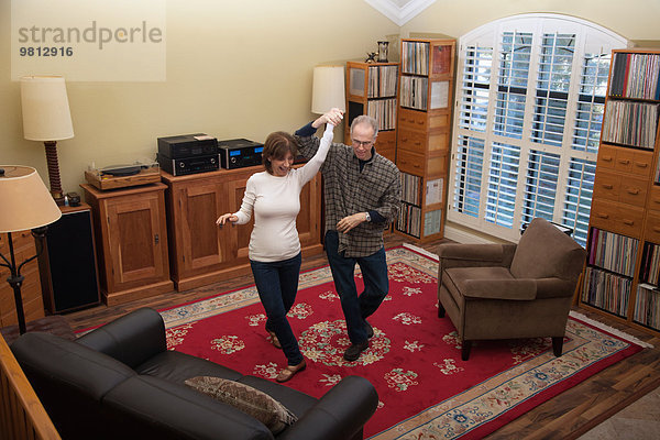 Seniorenpaar tanzt zusammen im Wohnzimmer