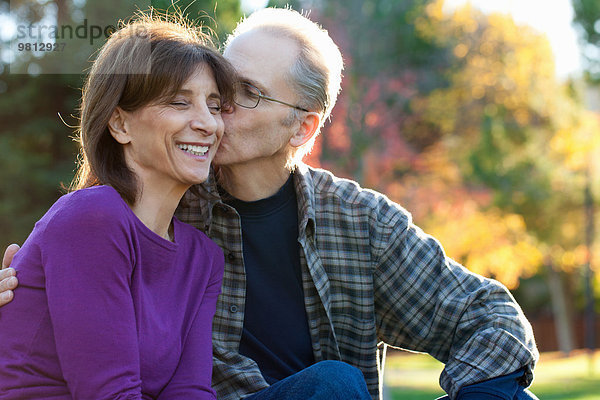 Senior Mann küsst Frau auf Wange im Garten