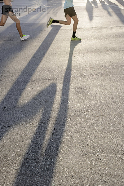 Beine von zwei reifen männlichen Läufern im Straßenlauf