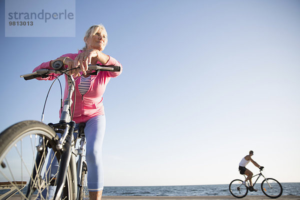 Seniorin auf dem Fahrrad am Strand