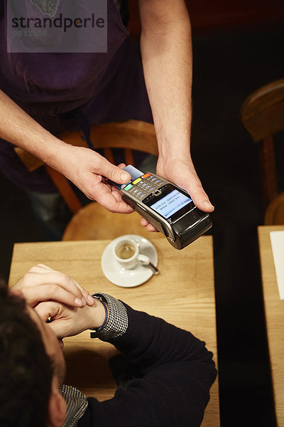 Mann  der seine Rechnung im Restaurant bezahlt  mit Kreditkarte  erhöhte Ansicht