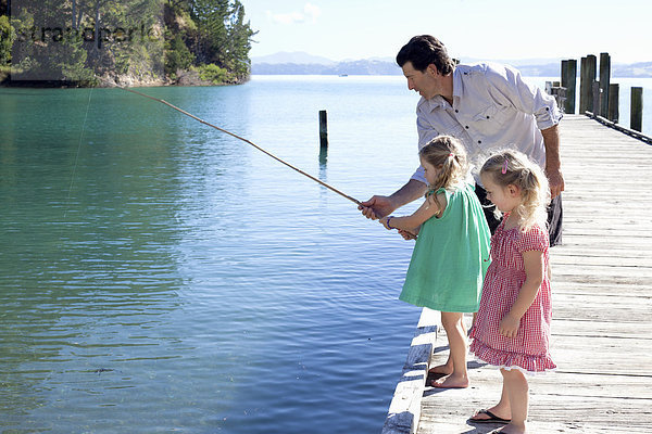 Erwachsener Mann und zwei junge Mädchen beim Angeln vom Pier  Neuseeland