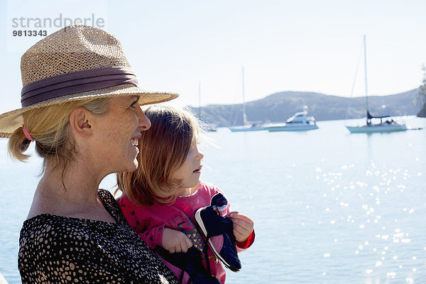 Porträt einer mittleren erwachsenen Frau und Kleinkind-Tochter an der Küste  Neuseeland