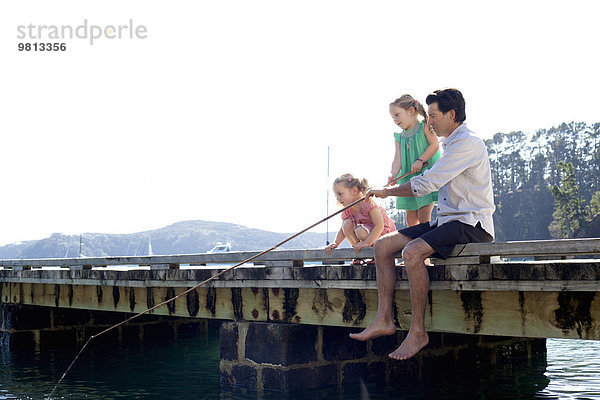 Erwachsener Mann und Tochter beim Fischen vom Pier aus  Neuseeland