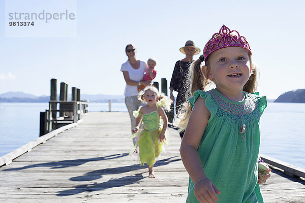Zwei erwachsene Frauen und Töchter  die am Pier spazieren und laufen  Neuseeland