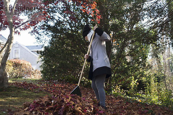 Gärtnerin rechend Herbstlaubhaufen im Park