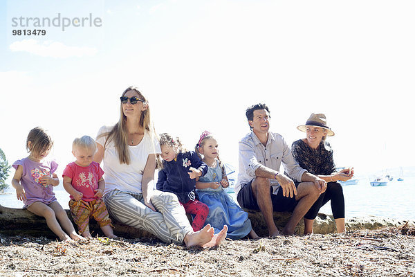 Familien und Töchter auf Baumstamm am Strand  Neuseeland