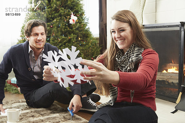 Junges Paar bereitet Schneeflockenschmuck zu Weihnachten vor