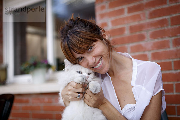 Porträt einer erwachsenen Frau und zögerlichen Katze vor der Haustür