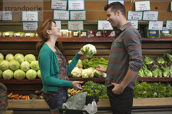 Mann und Frau chatten beim Einkaufen im Naturkostladen