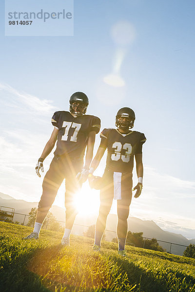 Porträt zweier amerikanischer Teenager-Fußballspieler bei Sonnenuntergang