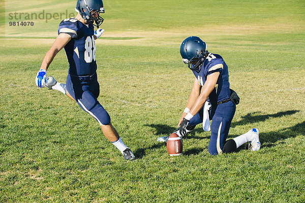 Teenager American Footballer Kick-Training auf dem Spielfeld