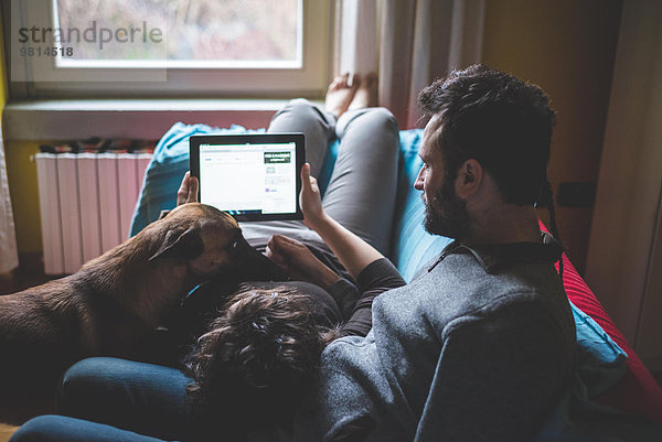 Paar auf Sofa liegend  mit digitalem Tablett