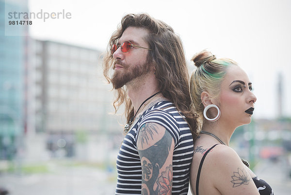 Porträt des Punk-Hippie-Paares Rücken an Rücken auf der City Street
