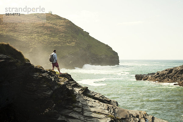 Mittlerer Erwachsener Mann  der von einer Felsenklippe  Boscastle  Cornwall  UK  hinausblickt.