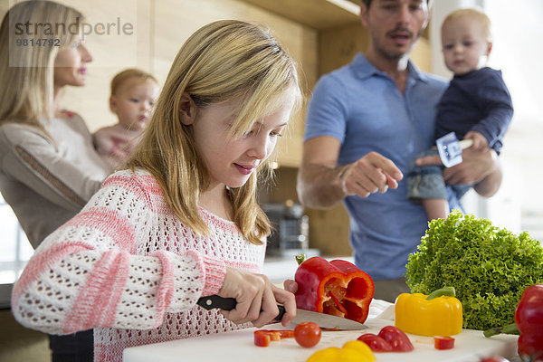 Mädchen mit Familie bei der Zubereitung von Paprika auf der Küchentheke