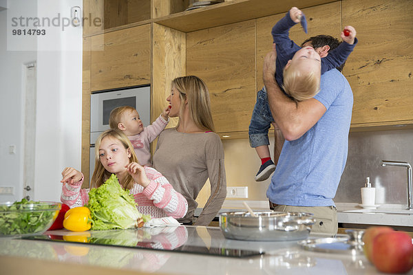 Mädchen mit Familie bei der Zubereitung von Gemüse auf der Küchentheke