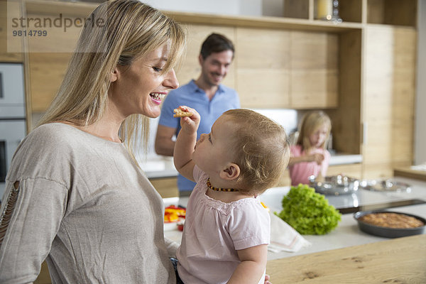 Weibliches Kleinkind füttert Mutter in der Küche