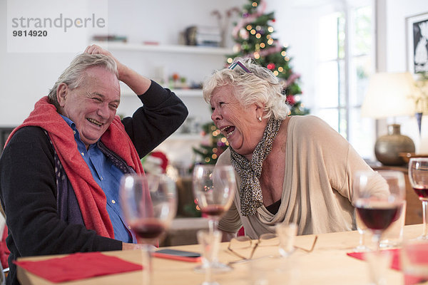 Seniorenpaar lacht am weihnachtlichen Mittagstisch