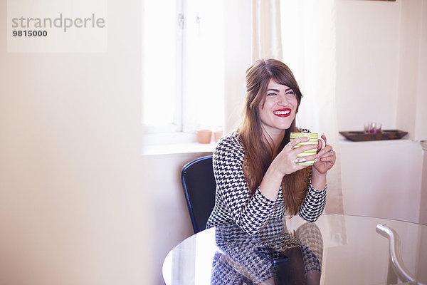 Frau am Tisch sitzend  Kaffee trinkend