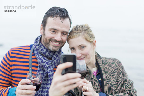 Paar am Strand  Wein trinken  Selbstporträt mit dem Smartphone machen