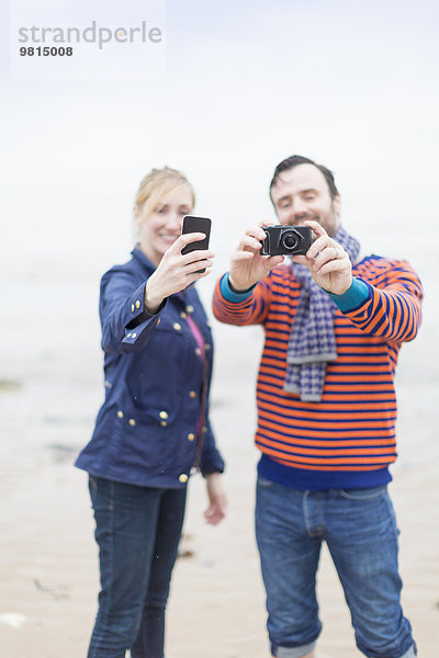 Paar im Freien  Fotografieren mit Kamera und Smartphone