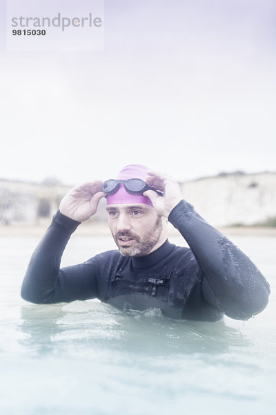 Erwachsener Mann im Meer  im Neoprenanzug  bereit zum Schwimmen