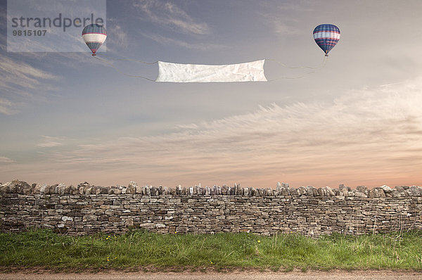 Banner zwischen zwei Heißluftballons über einer Cotswold-Steinwand