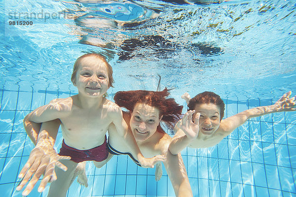 Unterwasseransicht von Mutter und zwei Söhnen beim Tauchen im Schwimmbad