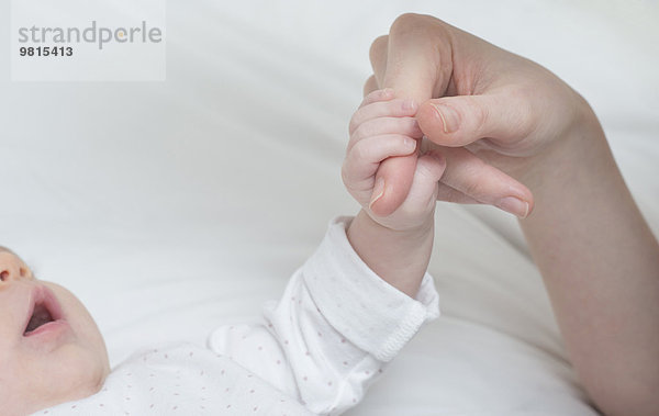 Kleines Mädchen mit dem Finger der Mutter im Bett