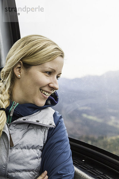 Junge Frau mit Blick aus dem Fenster im Skilift nach Osterfelderkopf  Garmisch-Partenkirchen  Bayern  Deutschland