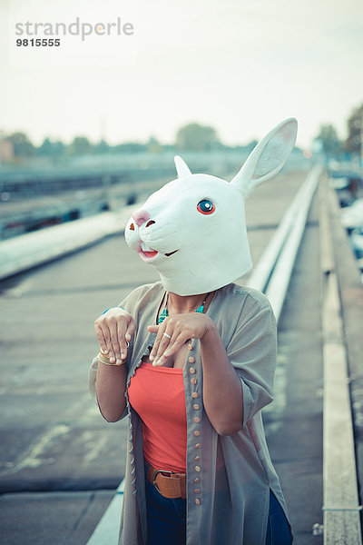 Junge Frau in Kaninchenkostüm Maske im städtischen Industriegebiet