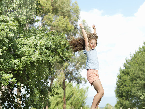 Teenager-Mädchen springt mit ausgestreckten Armen  im Freien