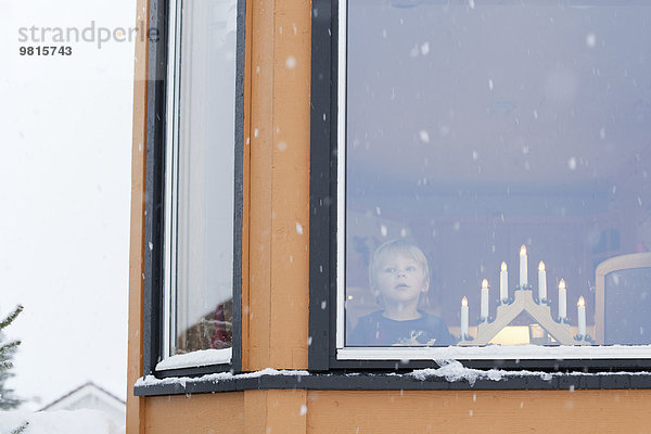 Junge wartet hinter dem Fenster