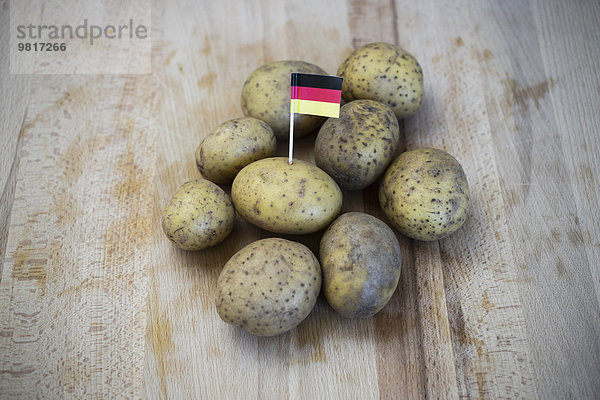 Reihenkartoffeln und kleine deutsche Fahne auf Holz
