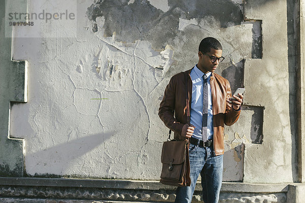 Geschäftsmann mit Smartphone in Lederjacke und Brille