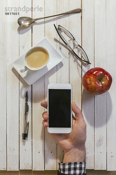 Männerhände mit Smartphone  Tasse Kaffee  Gläser  Apfel  Löffel und Stift