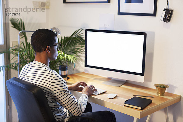 Junger kreativer Mann arbeitet am Computer in seinem Home-Office