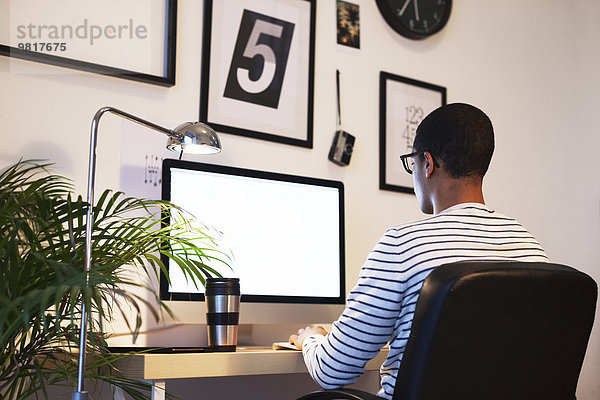 Junger kreativer Mann arbeitet am Computer in seinem Home-Office