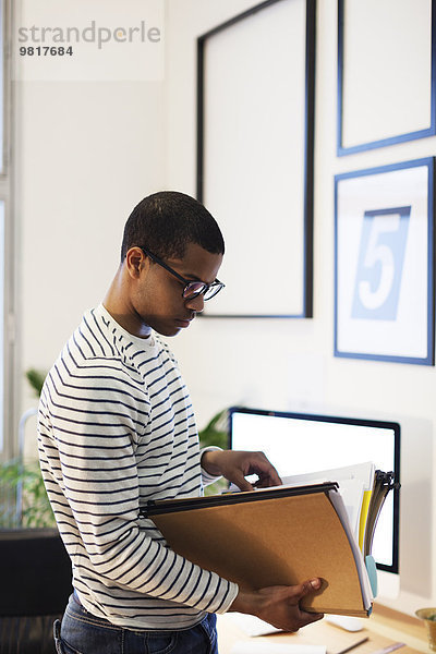 Junger kreativer Mann mit Akten in seinem Home-Office