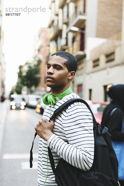 Spanien  Barcelona  junger Mann mit grünen Kopfhörern und Rucksack auf der Straße