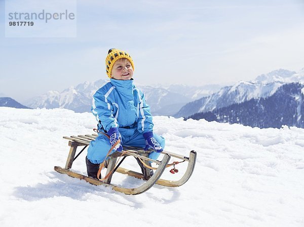 Deutschland  Tegernsee  Wallberg  lächelnder kleiner Junge auf Schlitten sitzend