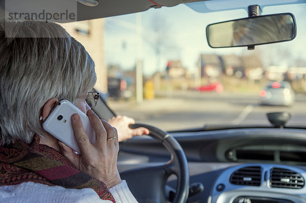 Seniorin im Auto am Handy