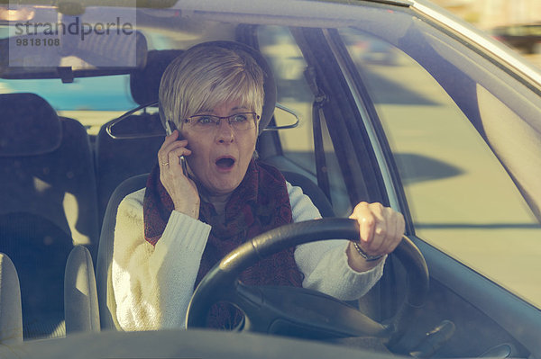 Ängstliche Seniorin im Auto am Handy