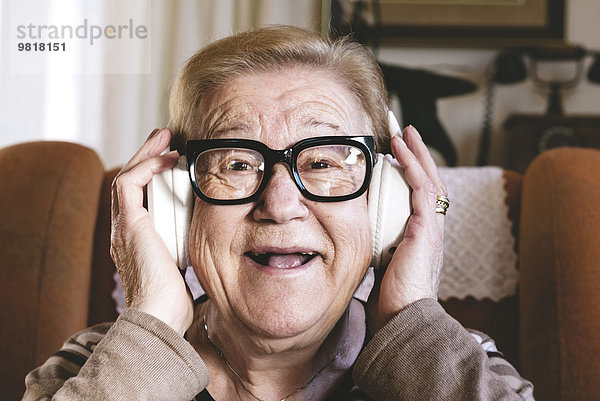 Portrait einer glücklichen älteren Dame  die Musik mit Kopfhörern hört.