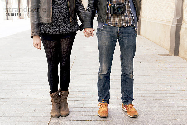 Mann und Frau halten sich auf der Straße an den Händen.