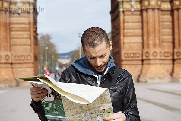 Spanien  Barcelona  Mann schaut auf Stadtplan vor dem Trymphalbogen